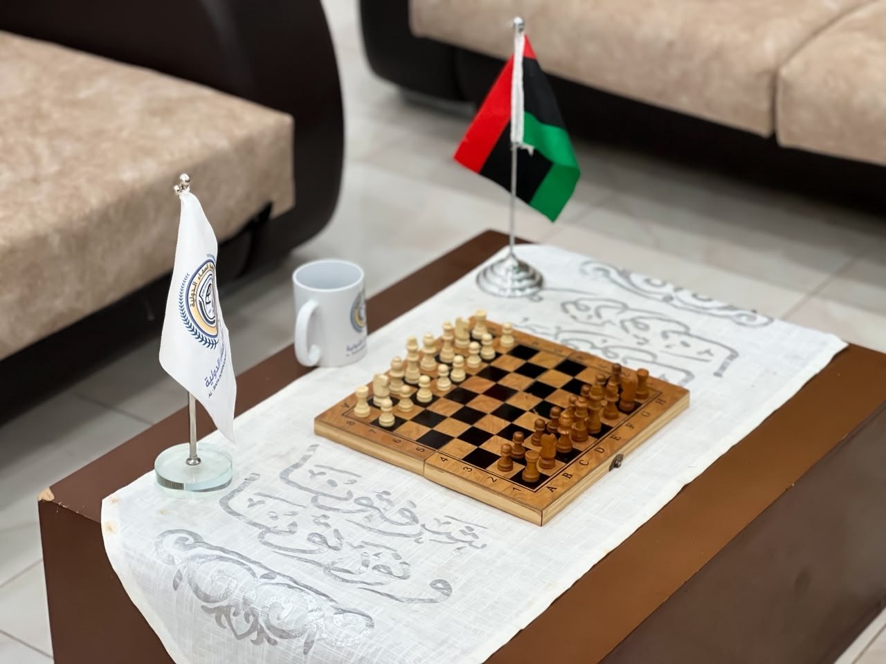 ركن استراحة في جامعة الصفاء الدولية يضم علم ليبيا وعلم الجامعة ورقعة شطرنج